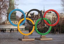 Iconic Olympic rings with city backdrop in Paris, capturing sports spirit.