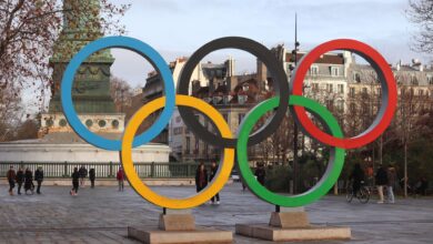 Iconic Olympic rings with city backdrop in Paris, capturing sports spirit.