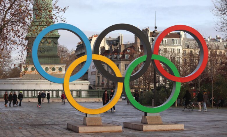 Iconic Olympic rings with city backdrop in Paris, capturing sports spirit.