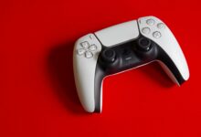 White DualSense controller for PlayStation 5 on a striking red backdrop, emphasizing modern gaming technology.