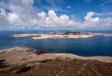 A breathtaking view of the Canary Islands coastline with clear blue waters and dramatic clouds.