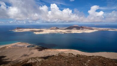 A breathtaking view of the Canary Islands coastline with clear blue waters and dramatic clouds.