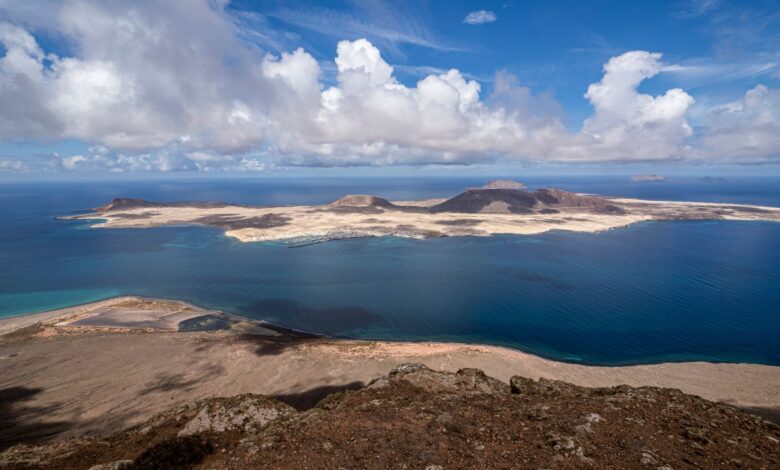 A breathtaking view of the Canary Islands coastline with clear blue waters and dramatic clouds.
