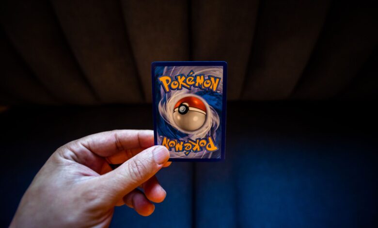 Crop unrecognizable person demonstrating collectible card dedicated to fictional creatures on dark background