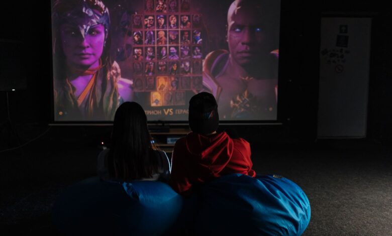 Two friends enjoying a video game session on a projector screen, immersed in gameplay.