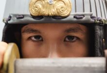 Close-up of a samurai warrior's eyes with a traditional helmet, holding a sword.