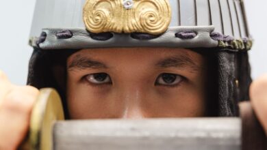 Close-up of a samurai warrior's eyes with a traditional helmet, holding a sword.