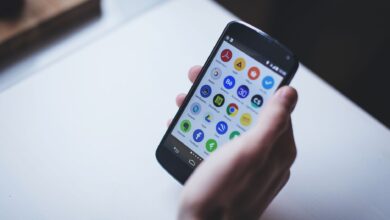 Close-up of a person holding a smartphone with various app icons visible on the screen.