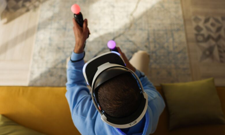 A person wearing virtual reality glasses and using controllers, viewed from above, indoors.
