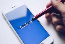 Close-up of a smartphone with a stylus crossing out text on its screen.