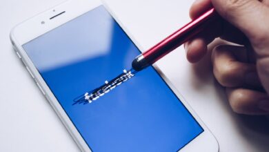 Close-up of a smartphone with a stylus crossing out text on its screen.