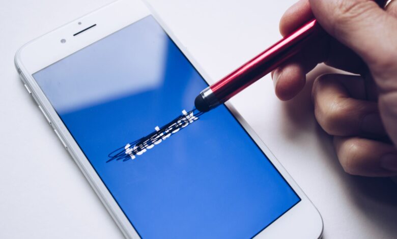 Close-up of a smartphone with a stylus crossing out text on its screen.