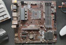 Close-up photo of an MSI B450M Pro-Vdh Plus motherboard on a desk.