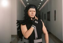 Cosplayer dressed as a dramatic anime character poses confidently in an indoor corridor.