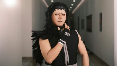 Cosplayer dressed as a dramatic anime character poses confidently in an indoor corridor.