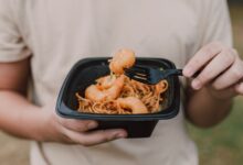 Tasty Asian noodles with shrimp being held in hands, ideal for food enthusiasts.