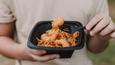 Tasty Asian noodles with shrimp being held in hands, ideal for food enthusiasts.