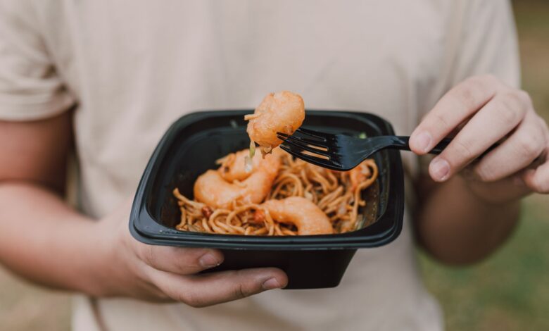 Tasty Asian noodles with shrimp being held in hands, ideal for food enthusiasts.