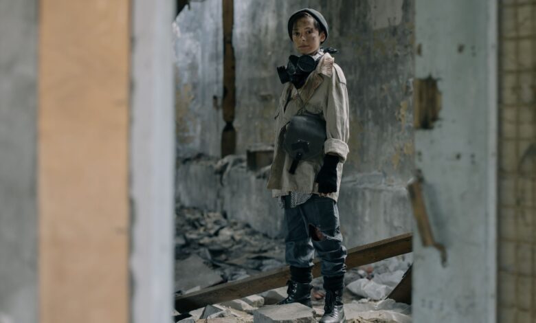 Young person in protective gear stands in a desolate, abandoned building, symbolizing survival.