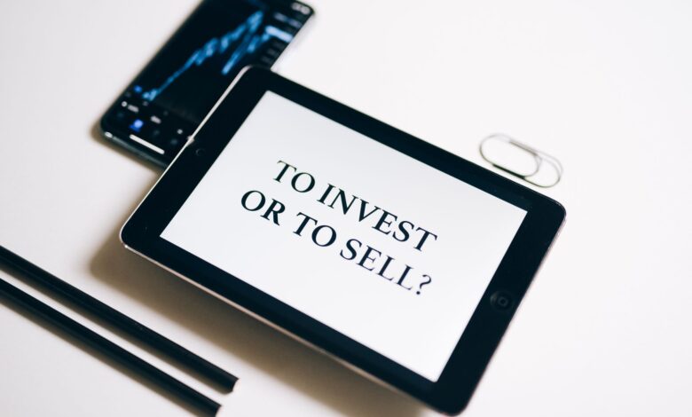 A tablet with text 'To Invest or To Sell?' on a white background.
