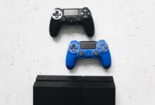 Two game controllers placed on a white surface above a gaming console.
