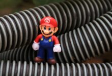 Close-up of a Super Mario toy figure standing among coiled plastic tubes.