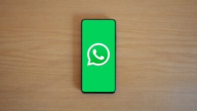 Top view of smartphone displaying WhatsApp logo on a wooden background, representing technology and communication.