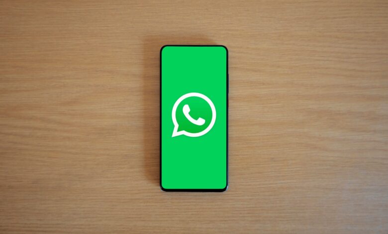 Top view of smartphone displaying WhatsApp logo on a wooden background, representing technology and communication.