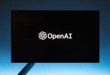 Minimalist display of OpenAI logo on a screen, set against a gradient blue background.