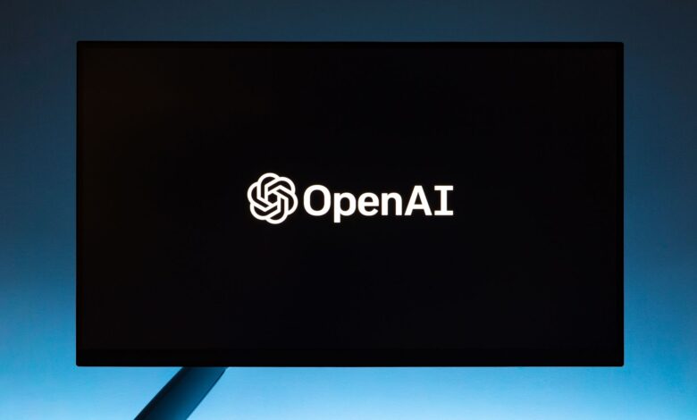 Minimalist display of OpenAI logo on a screen, set against a gradient blue background.