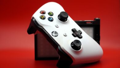 Close-up of a white gaming controller with black buttons against a vivid red backdrop.