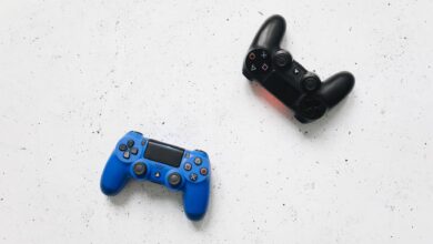 Top view of black and blue PlayStation game controllers on a speckled white surface.