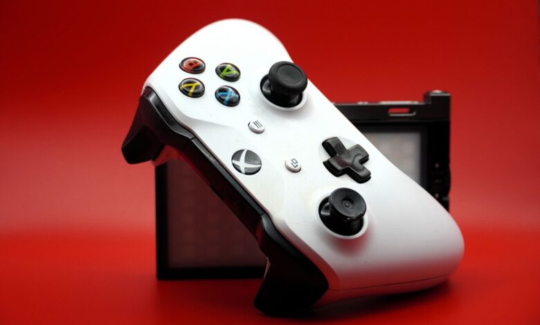 Close-up of a white gaming controller with black buttons against a vivid red backdrop.