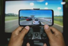 Close-up of hands playing a racing game on a mobile device with a controller.