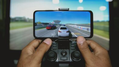 Close-up of hands playing a racing game on a mobile device with a controller.