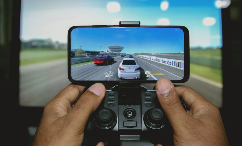 Close-up of hands playing a racing game on a mobile device with a controller.