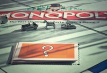 Close-up of Monopoly board game with metal tokens and dice in warm light.