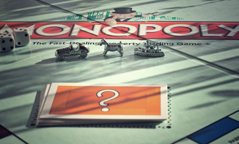 Close-up of Monopoly board game with metal tokens and dice in warm light.
