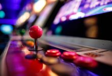 Close-up of a vibrant retro arcade joystick and buttons with blurred lights in the background.