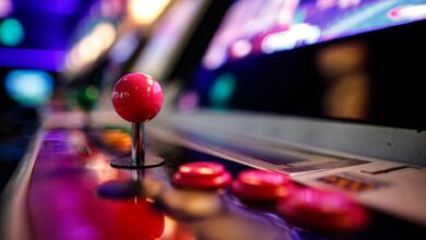 Close-up of a vibrant retro arcade joystick and buttons with blurred lights in the background.