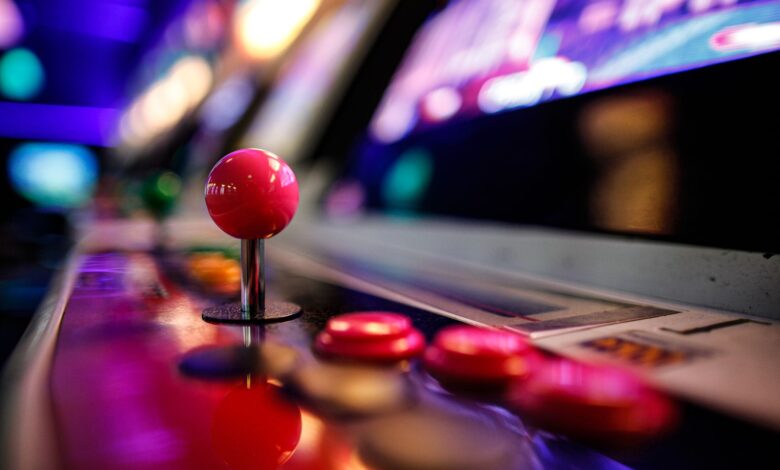 Close-up of a vibrant retro arcade joystick and buttons with blurred lights in the background.