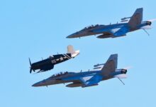 Jet fighters fly in formation with a vintage warplane against a clear blue sky.