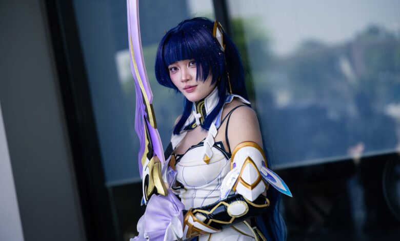 A cosplayer dressed in detailed futuristic armor wielding a long sword outdoors.