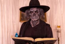 Person in gothic costume reading a book in a dimly lit room, creating a mysterious atmosphere.