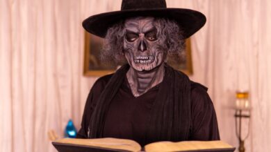 Person in gothic costume reading a book in a dimly lit room, creating a mysterious atmosphere.