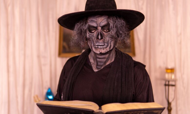Person in gothic costume reading a book in a dimly lit room, creating a mysterious atmosphere.