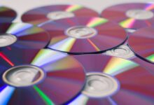 Stack of colorful CDs reflecting light, showcasing vibrant refractions and round patterns.