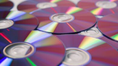 Stack of colorful CDs reflecting light, showcasing vibrant refractions and round patterns.