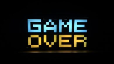 Illuminated pixel art 'Game Over' sign with vibrant colors against a black background.