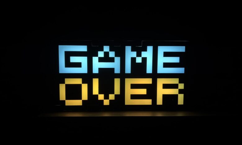 Illuminated pixel art 'Game Over' sign with vibrant colors against a black background.